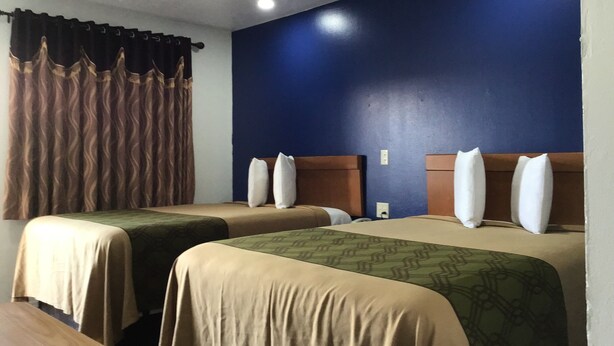 Una habitación de hotel con dos camas, paredes azul oscuro y una ventana con cortinas marrones.