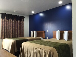 Una habitación de hotel con dos camas, paredes azul oscuro y una ventana con cortinas marrones.