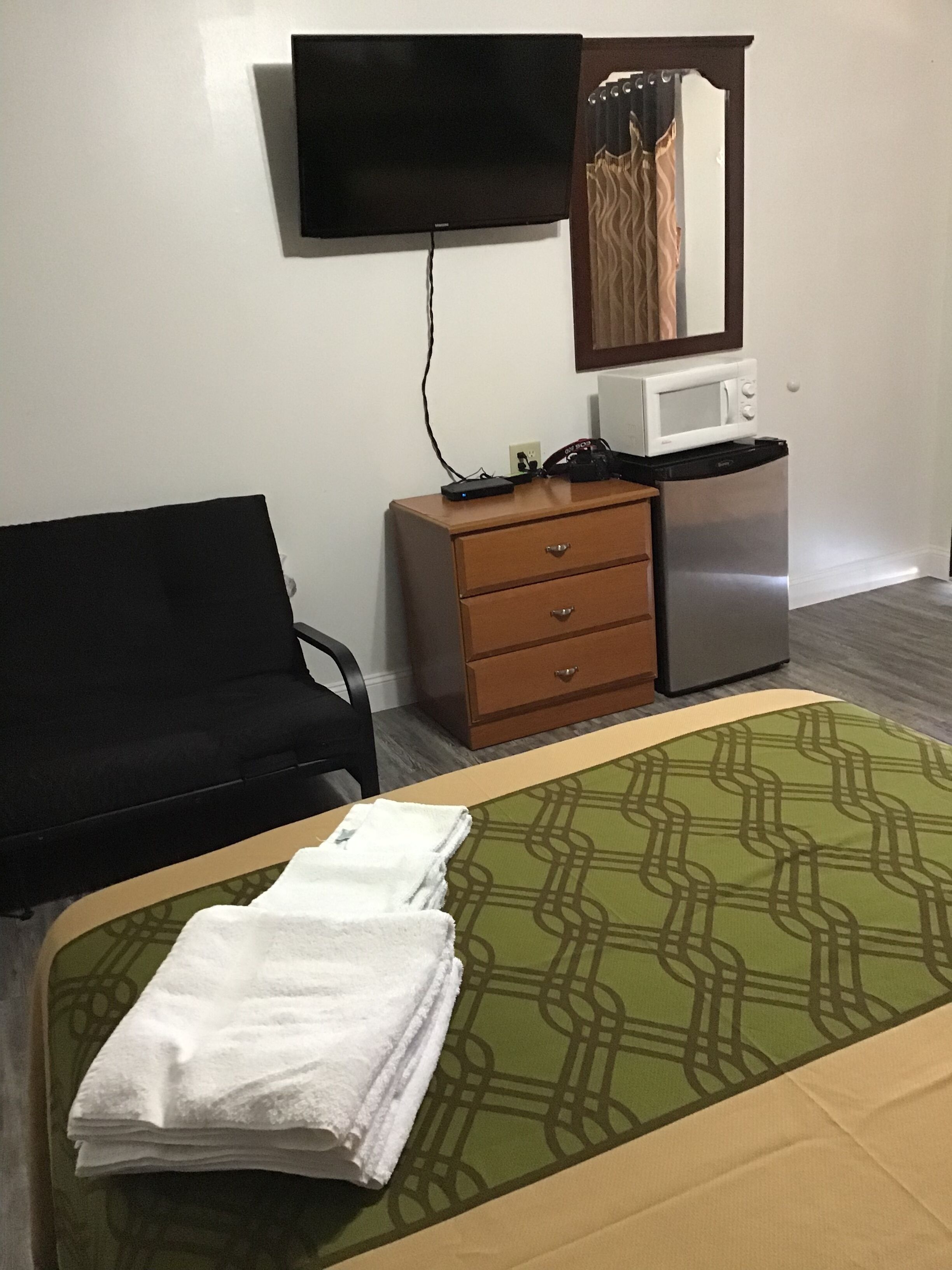 Hotelkamer met een bed, een slaapbank, een dressoir, een magnetron en een flatscreen televisie aan de muur.