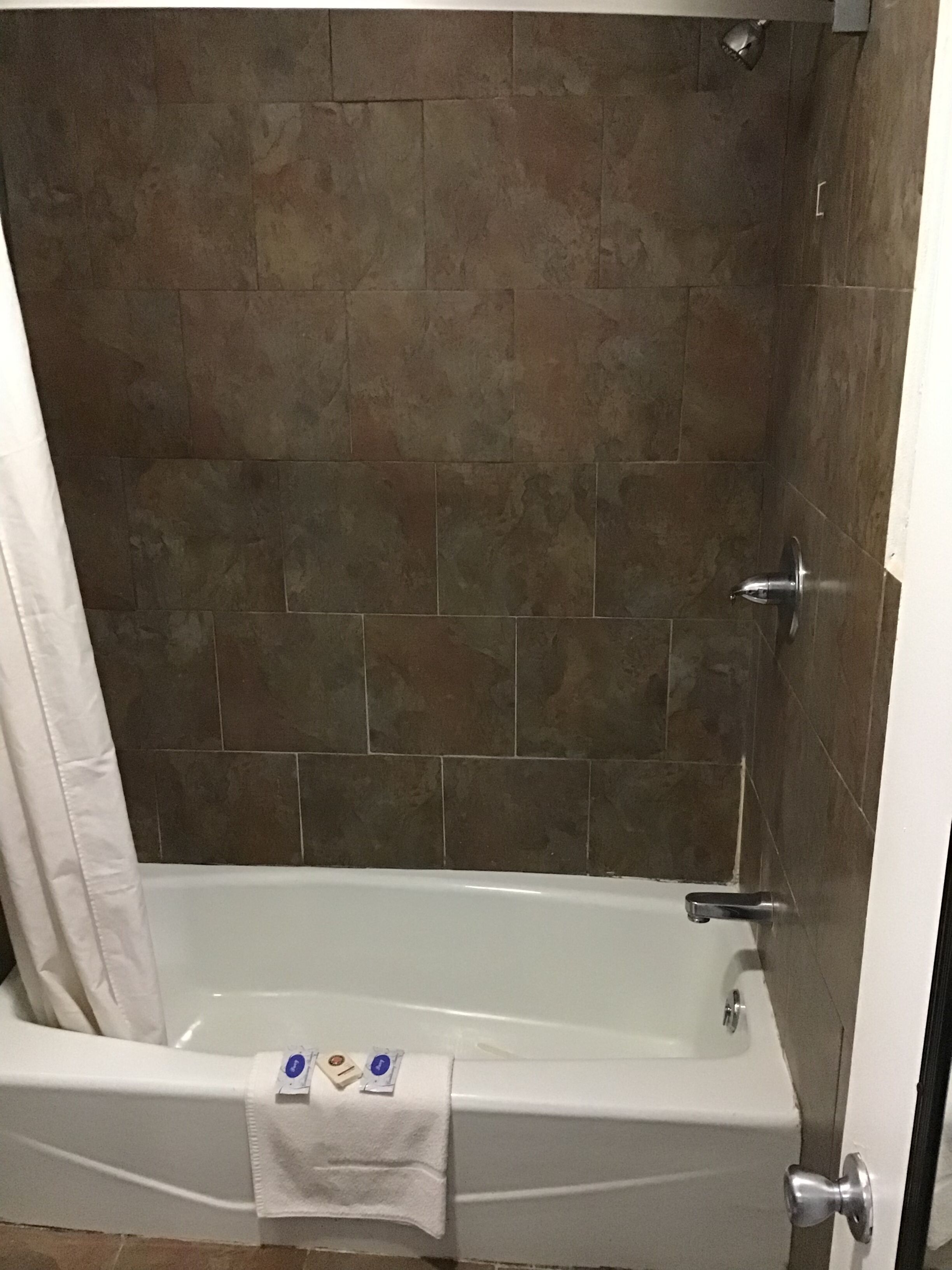 A bathroom with a bathtub, a shower, and a tiled wall.