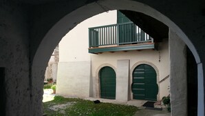 An arched corridor with a small balcony, two green doors, and a stone wall. - B&B Al Gatto Nero (Borgo Valsugana)