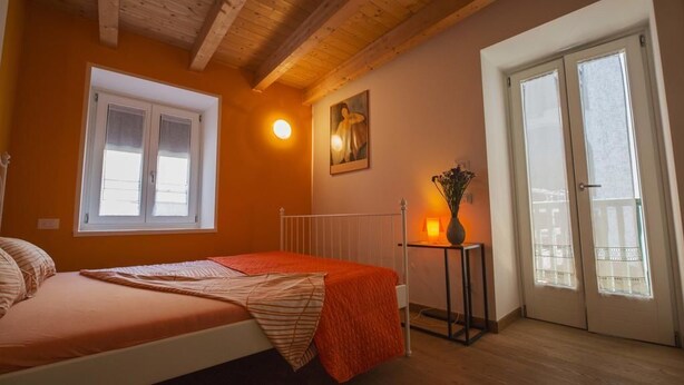 A bedroom with a bed, a window, a door, and a painting on the wall. - B&B Al Gatto Nero (Borgo Valsugana)