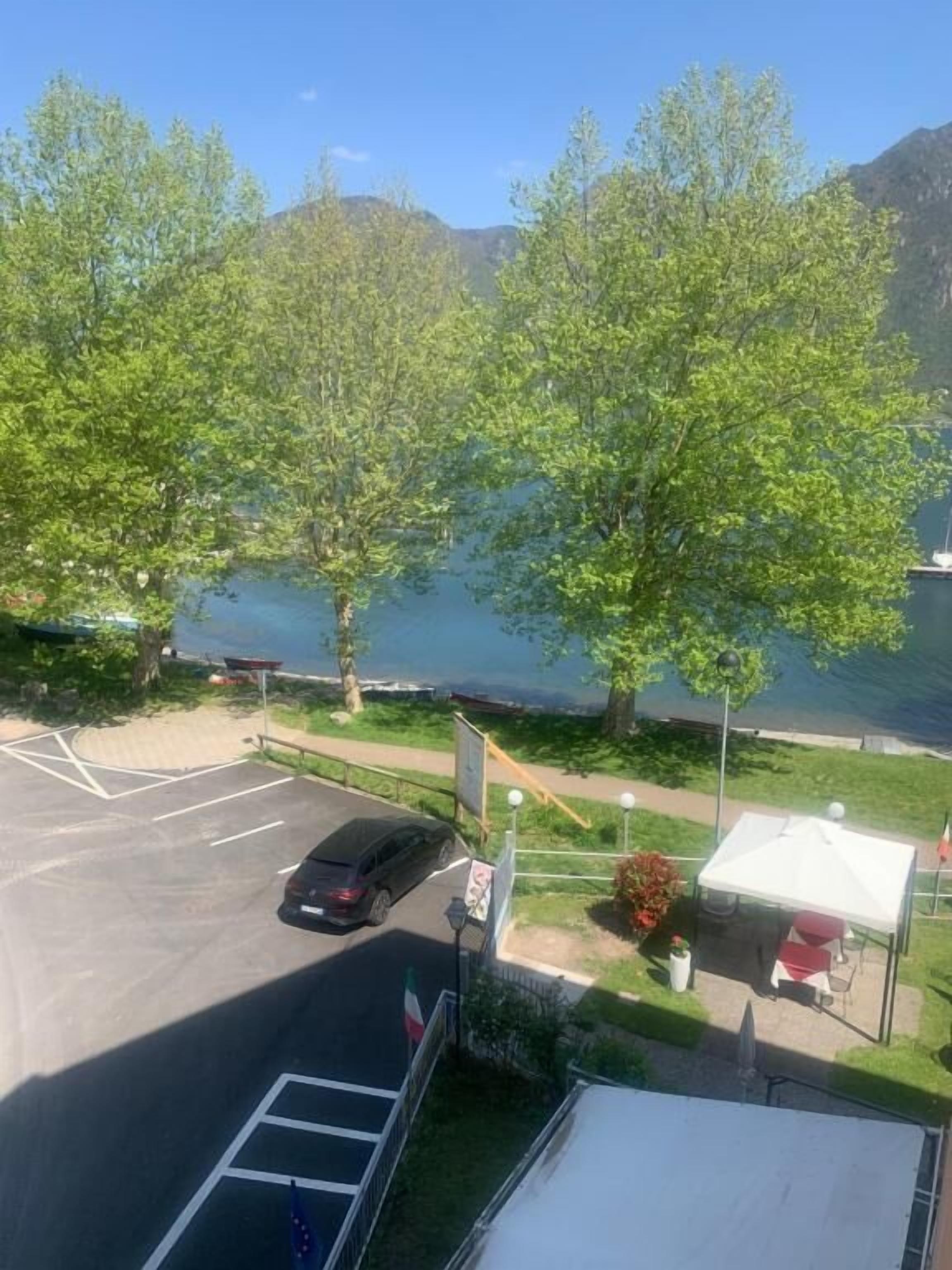 A parking lot with a car, a tent, and a body of water in the background.