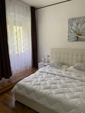 A bedroom with a bed, a nightstand, a lamp, and a wall-mounted artwork. - Hotel al Lago (Anfo)