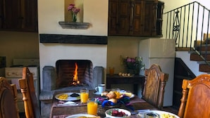 A dining table set with breakfast items, a fireplace, wooden cabinets, and a staircase. - Casita San Sebastián (Antigua Guatemala)