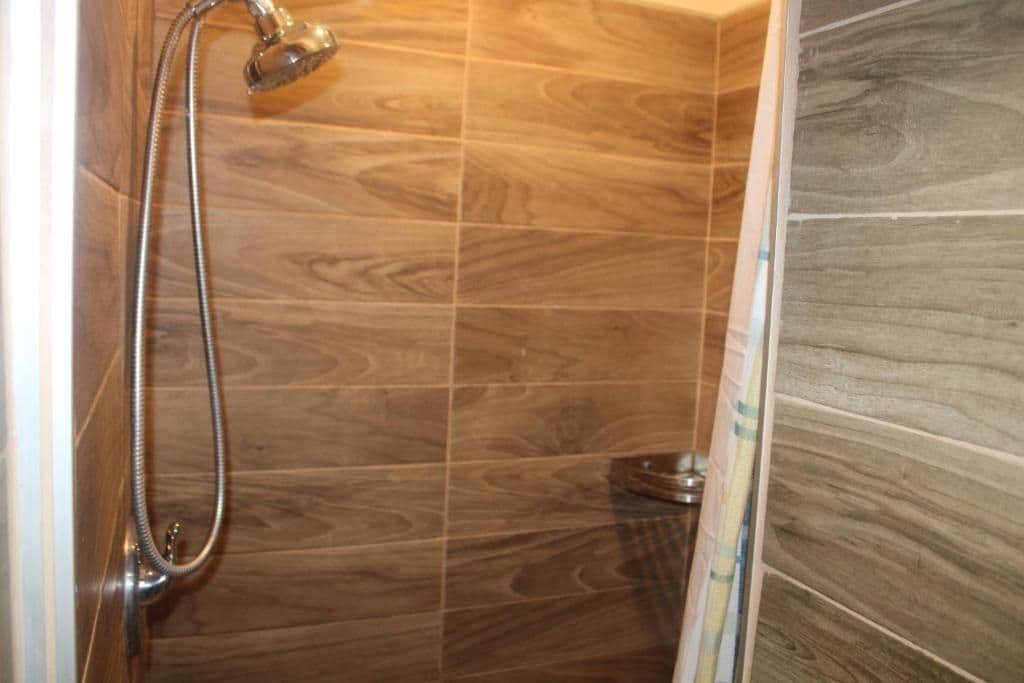 A shower with a handheld showerhead and a wall-mounted faucet.