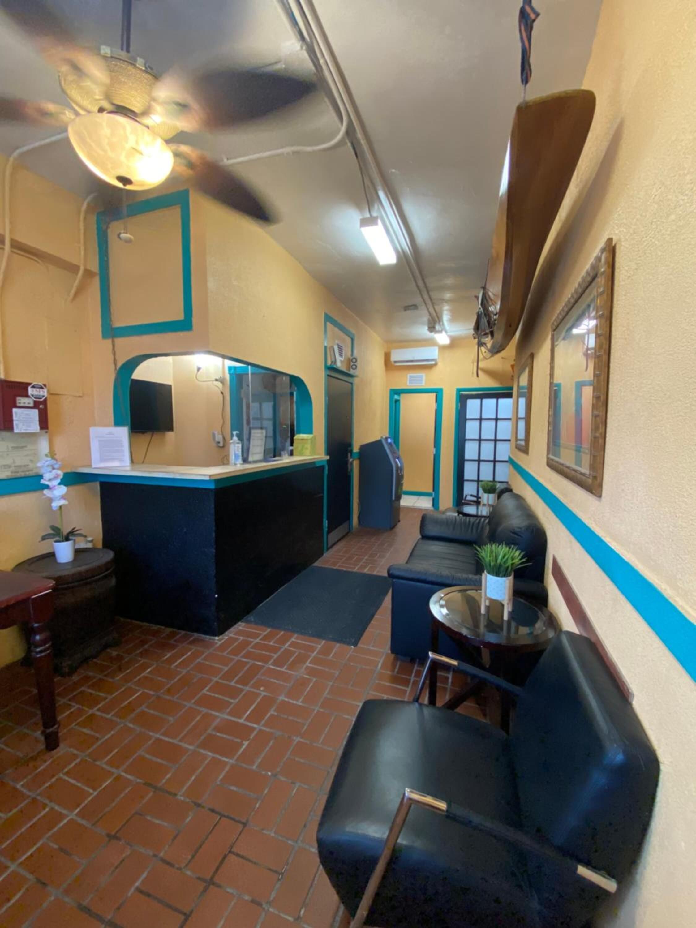 Una hall d'albergo con reception, area salotto e ventilatore a soffitto.
