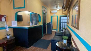Una hall d'albergo con reception, area salotto e ventilatore a soffitto.