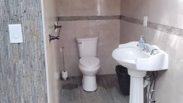 A bathroom with a toilet, sink, and shower.