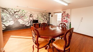 Un comedor con una mesa y sillas de madera, un mural en la pared y una puerta que da al exterior.