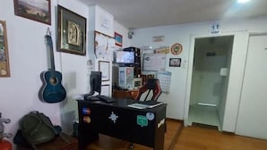 Una habitación con un escritorio, una guitarra, una silla y una puerta.