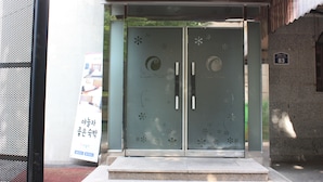 A building entrance with a glass door featuring decorative patterns and a sign above it. - Coups (Seoul)