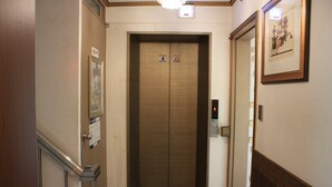 An elevator with a control panel, a door with a sign, and a framed picture on the wall. - Coups (Seoul)