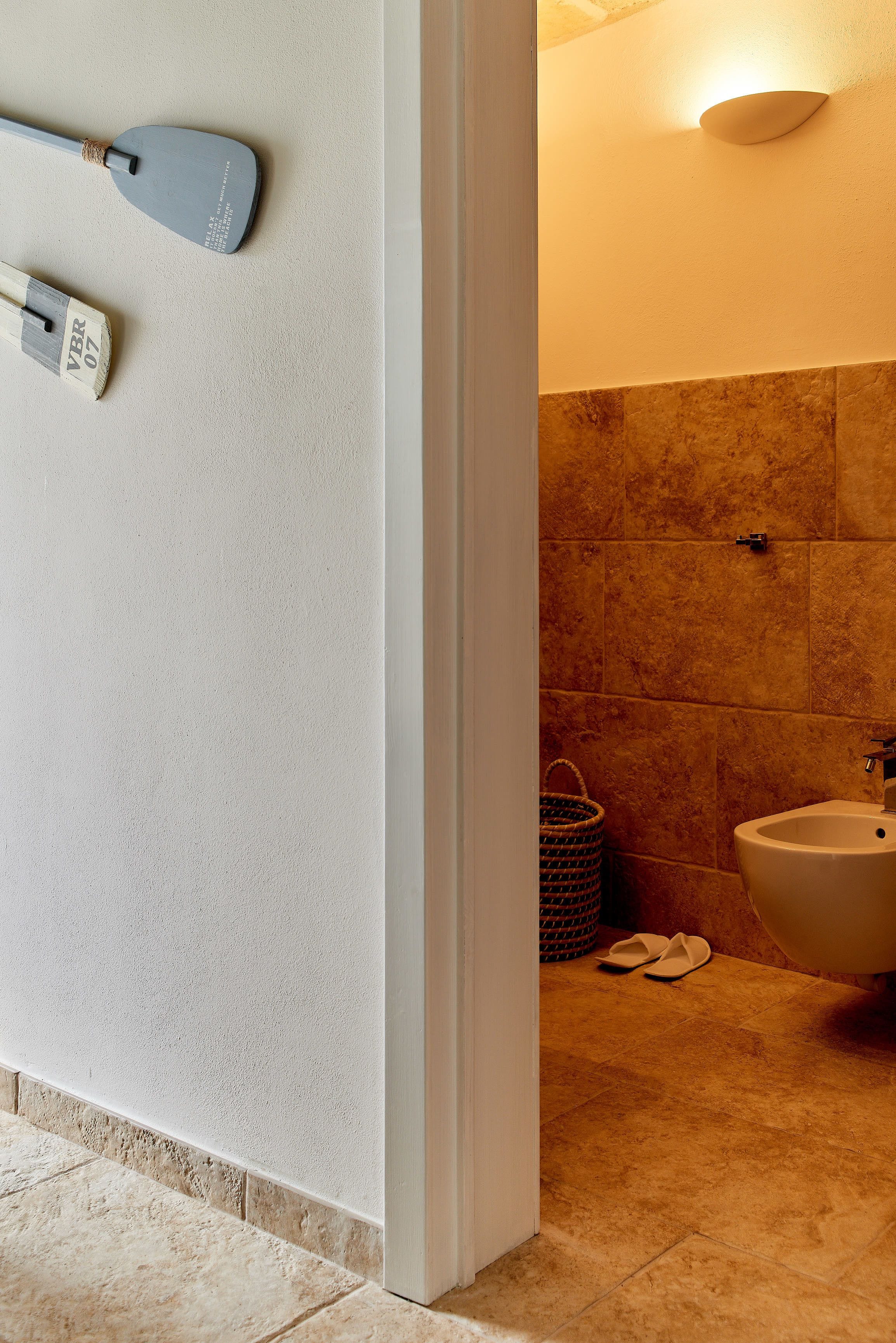 A bathroom with a white wall, a beige bathtub, and a white sink.