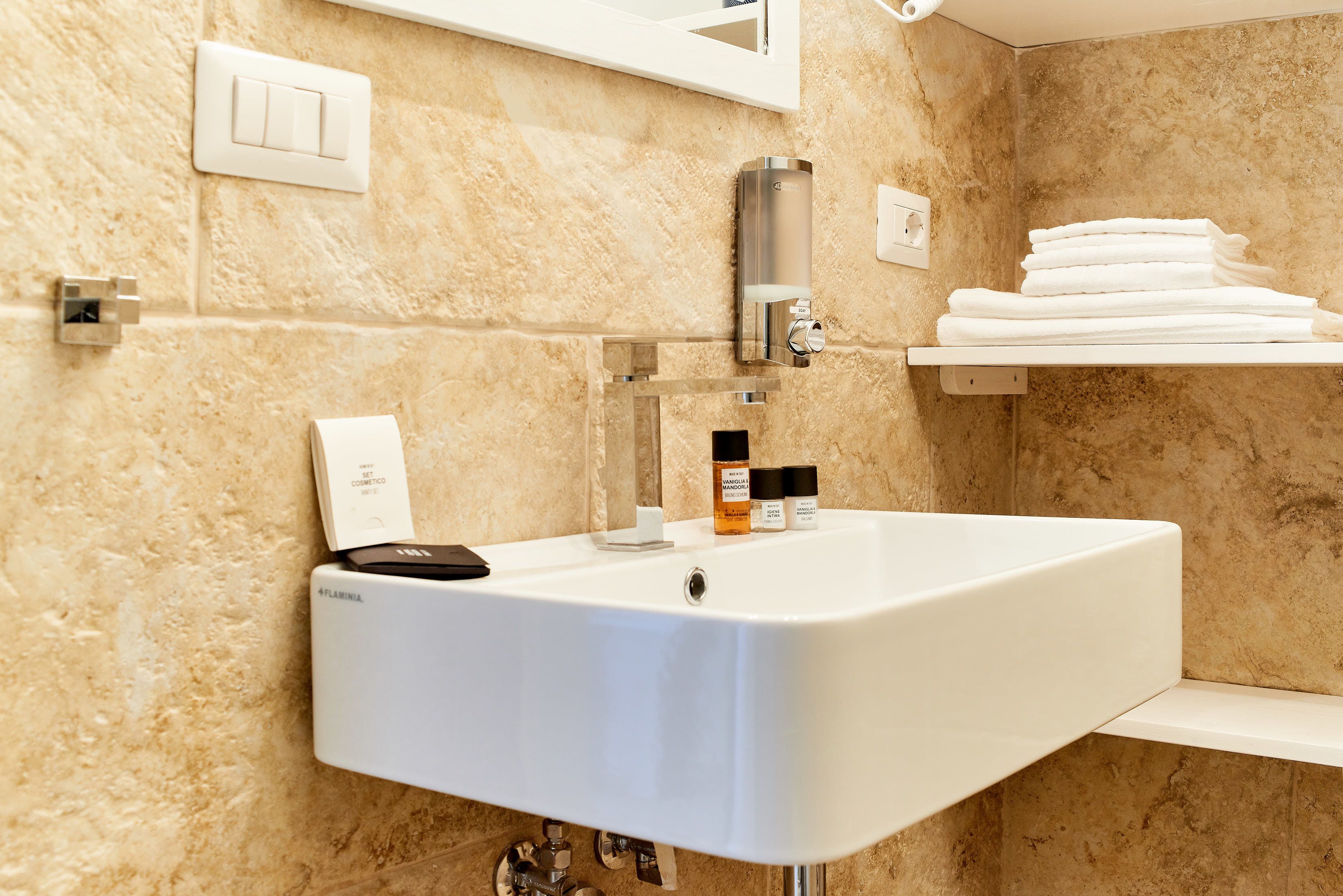 Een badkamer met een witte wastafel, een spiegel, een handdoekhouder en toiletartikelen.