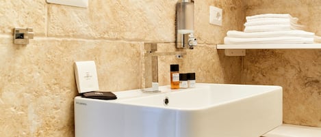 Een badkamer met een witte wastafel, een spiegel, een handdoekhouder en toiletartikelen.