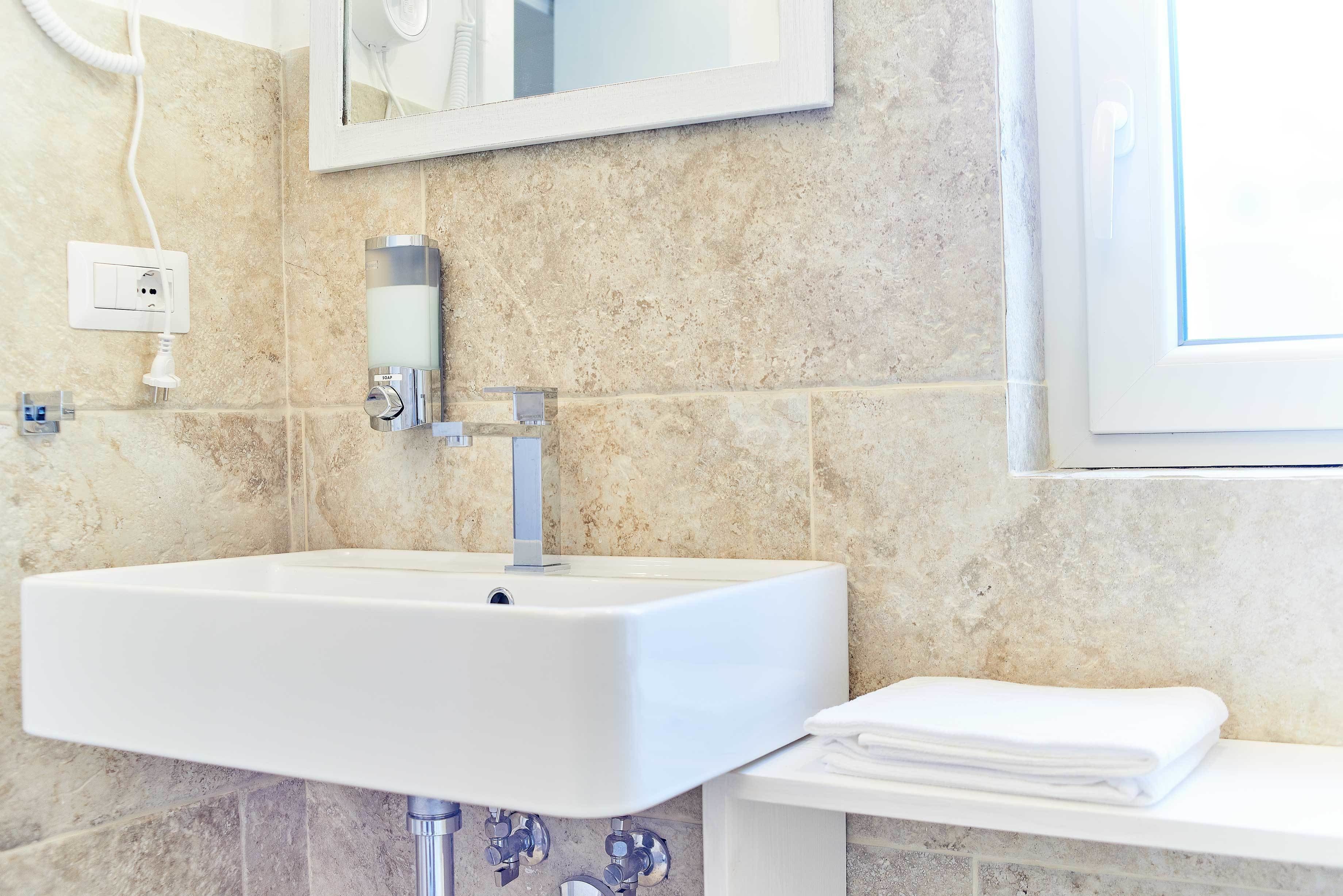 A bathroom with a white sink, a mirror, and a towel rack.