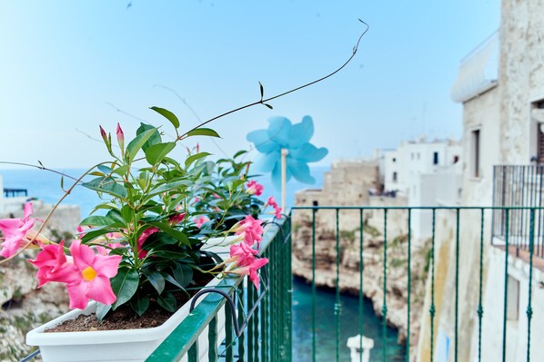 A balcony with potted plants and a view of a narrow waterway.