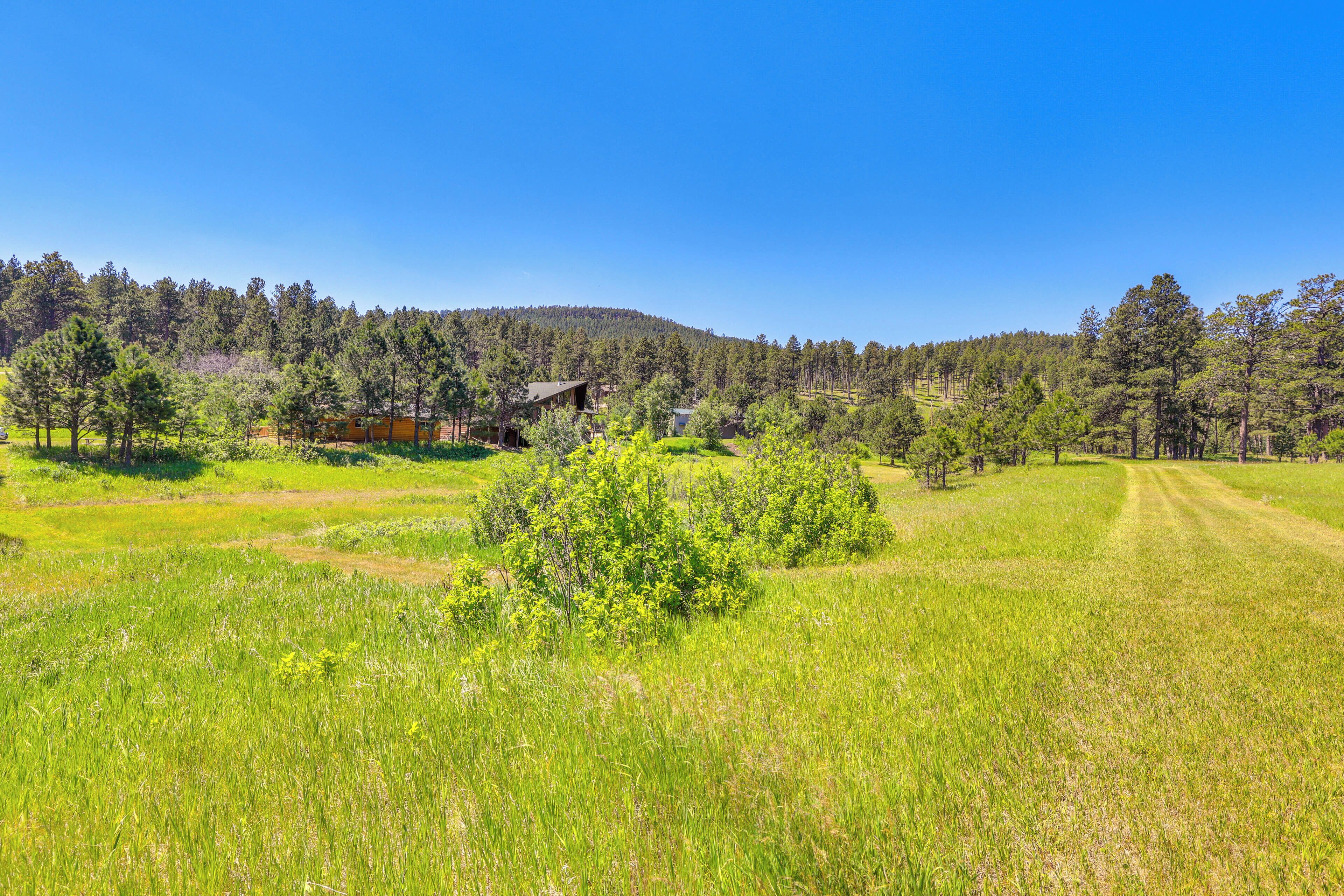 Paisaje rural con una casa rodeada de árboles y campos abiertos.