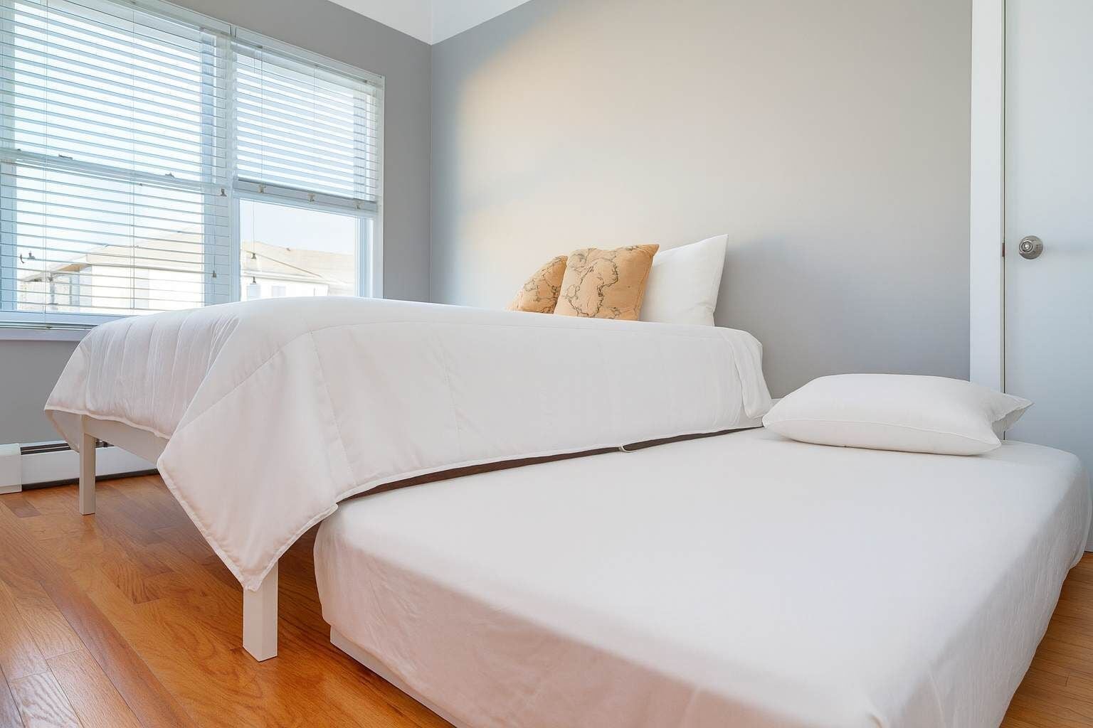 A bedroom with a bed, a window with blinds, and a door.