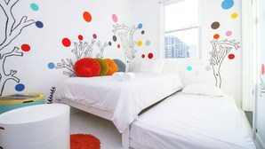 Une chambre à coucher avec un lit, une fenêtre et un mur décoré de motifs colorés en forme de points et d’arbres.