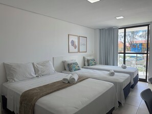 A hotel room with two beds, a large window with a view, and a ceiling light. - Laguna Suites (Ipojuca)