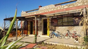 Un edificio rústico con fachada de piedra, un porche cubierto y bicicletas estacionadas afuera.