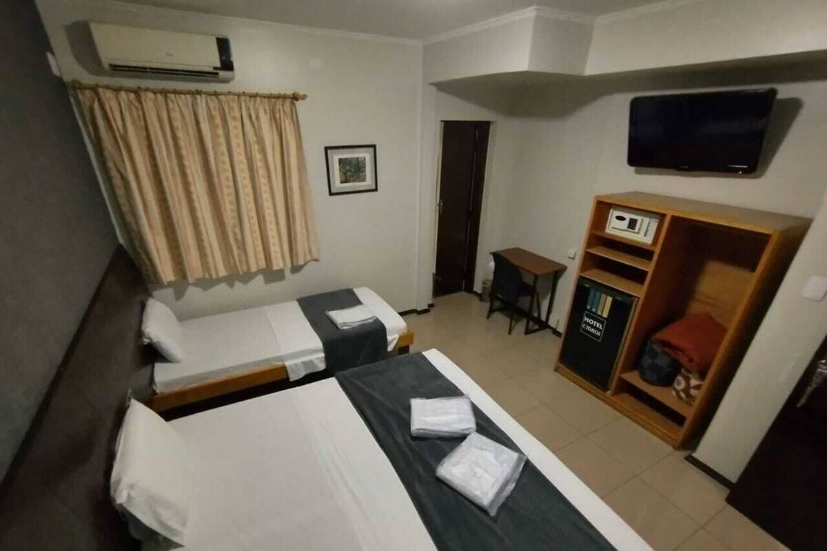 A hotel room with two beds, a desk, a television, and a wardrobe.