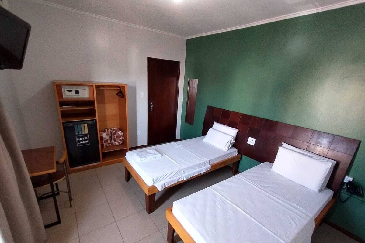A hotel room with two beds, a wardrobe, and a desk.