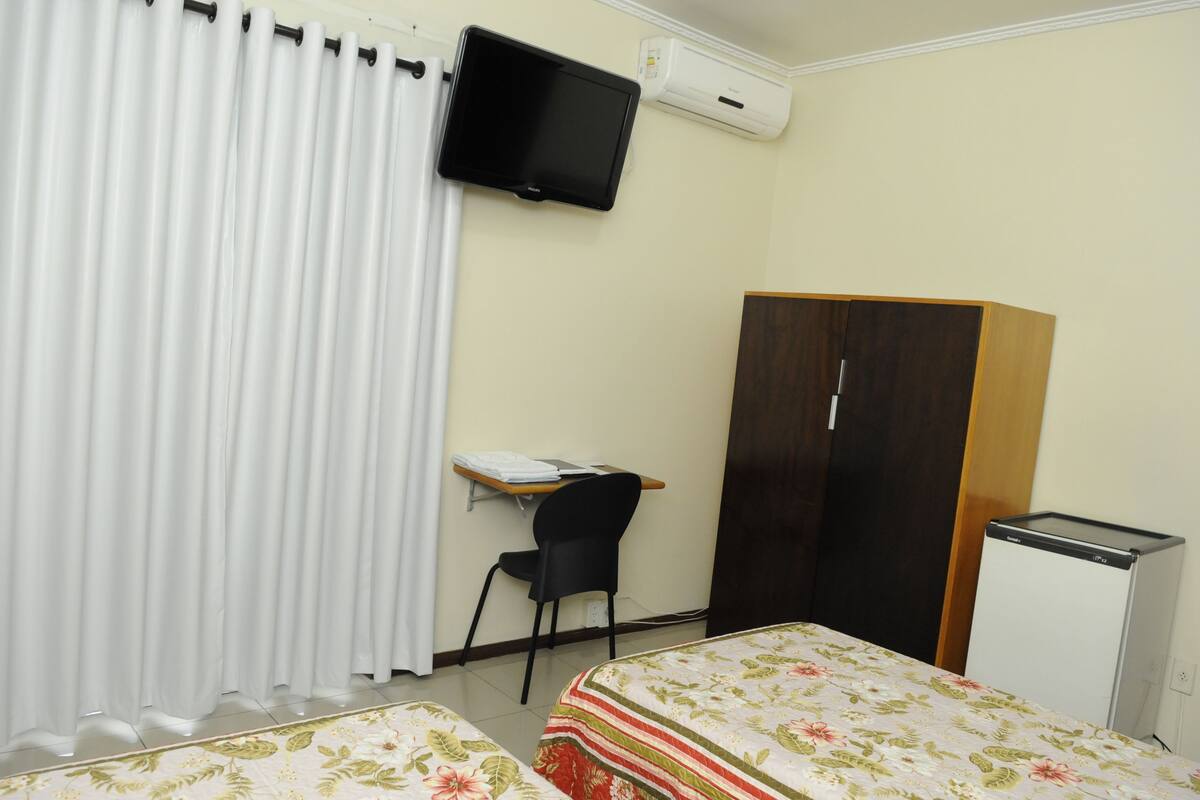 A room with a bed, a desk, a chair, a wardrobe, and a television.