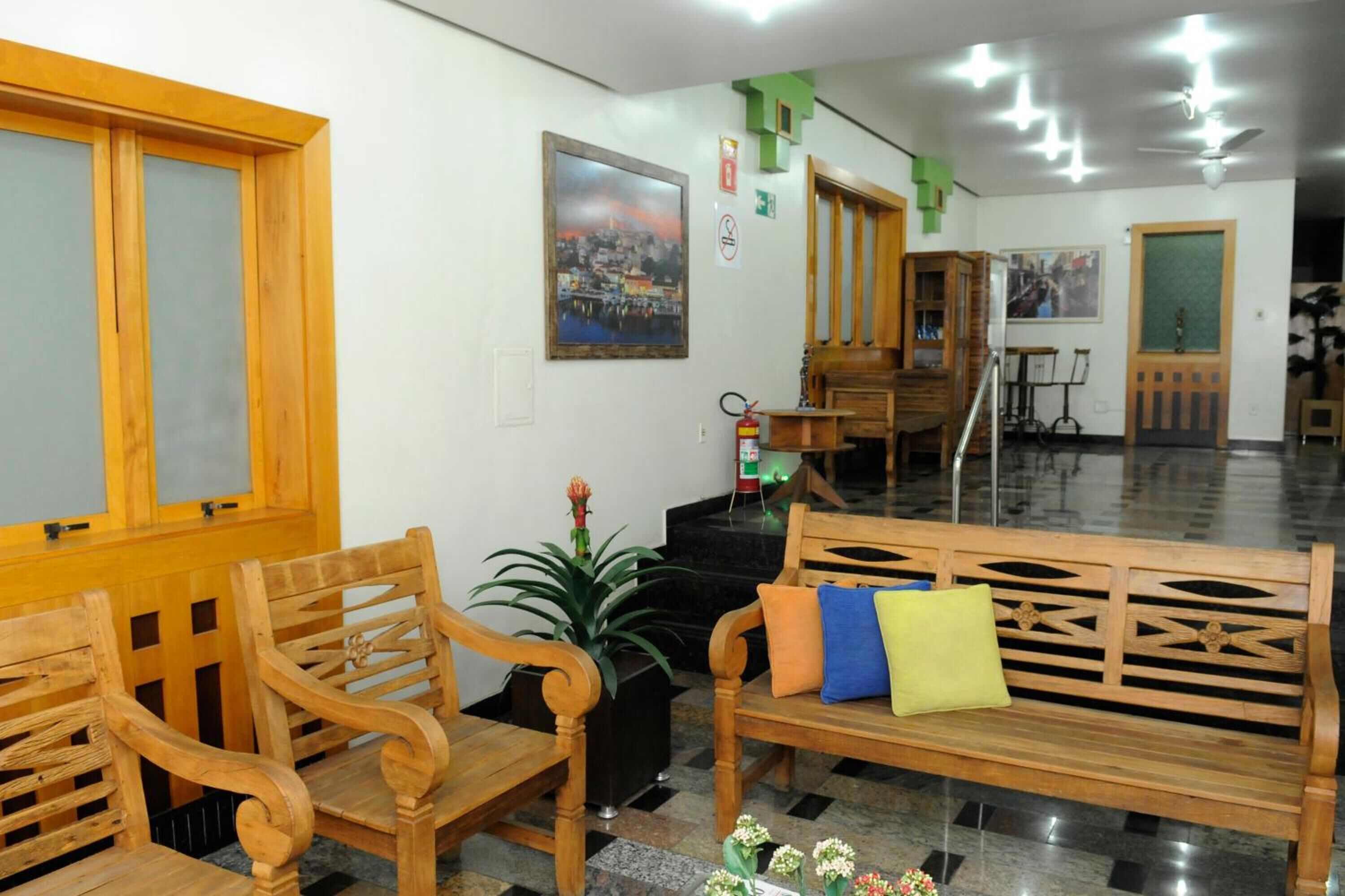 Un área de recepción con muebles de madera, una planta en maceta y un cuadro en la pared.