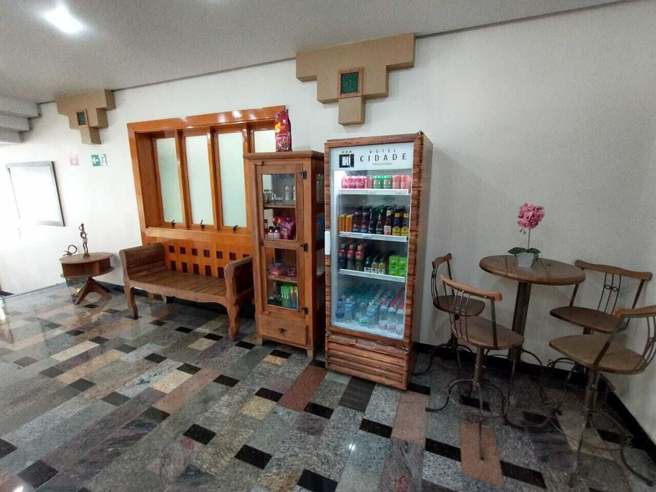 Eine Hotelhalle mit einer Rezeption, einer hölzernen Bank, einem Verkaufsautomaten und einem kleinen Tisch mit Stühlen.