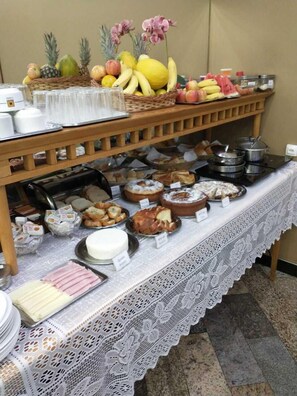 A buffet setup with various food items and a decorative tablecloth.