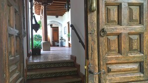 A wooden door with a brass handle, leading to a staircase with patterned steps and a wooden railing. - Casa Hermano Pedro (Antigua Guatemala)