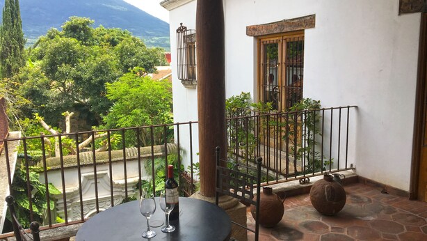 A balcony with a table, two wine glasses, and a bottle of wine. - Casa Hermano Pedro (Antigua Guatemala)