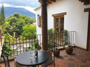 A balcony with a table, two wine glasses, and a bottle of wine. - Casa Hermano Pedro (Antigua Guatemala)