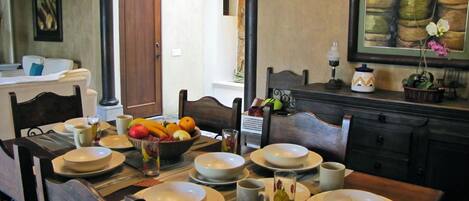 A dining area with a table set for four, including plates, bowls, and a fruit bowl.