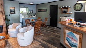 A modern kitchen with light blue cabinets, a dining area with wooden chairs and a table, and a reception desk with a sign for 'Townsend River Breeze Inn'.