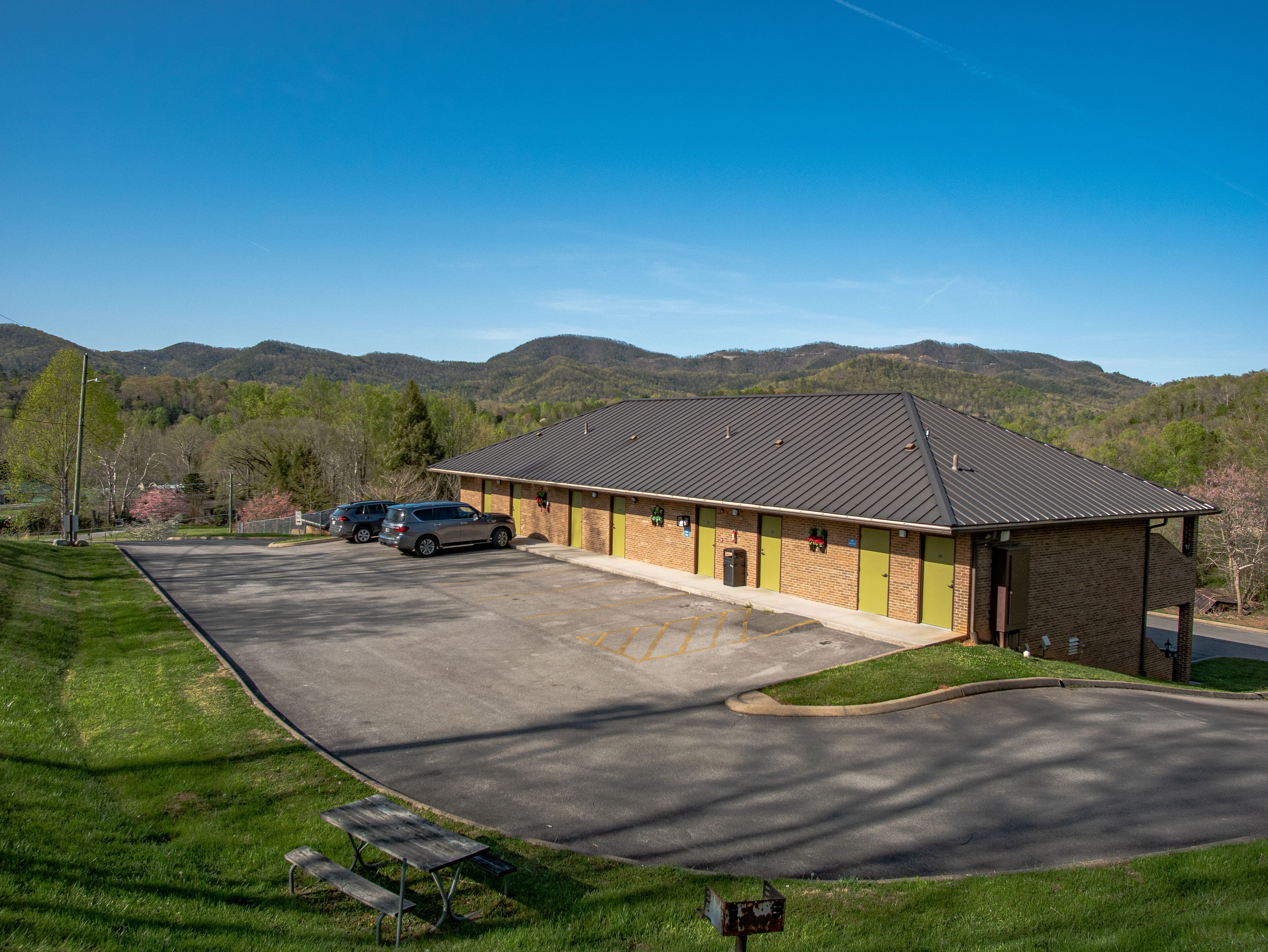 Ein Motel mit Parkplatz, überdachter Außenbestuhlung und Bergblick.