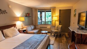 A hotel room with a bed, a sofa, a chair, a TV, and a window with curtains.