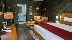 A hotel room with a large bed, a sofa, a small table, a lamp, and a mirror.