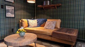 A cozy living room with a sofa, a round wooden coffee table, and a hanging light fixture.