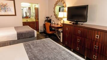 A hotel room with two beds, a desk with a chair, a television, and a dresser.