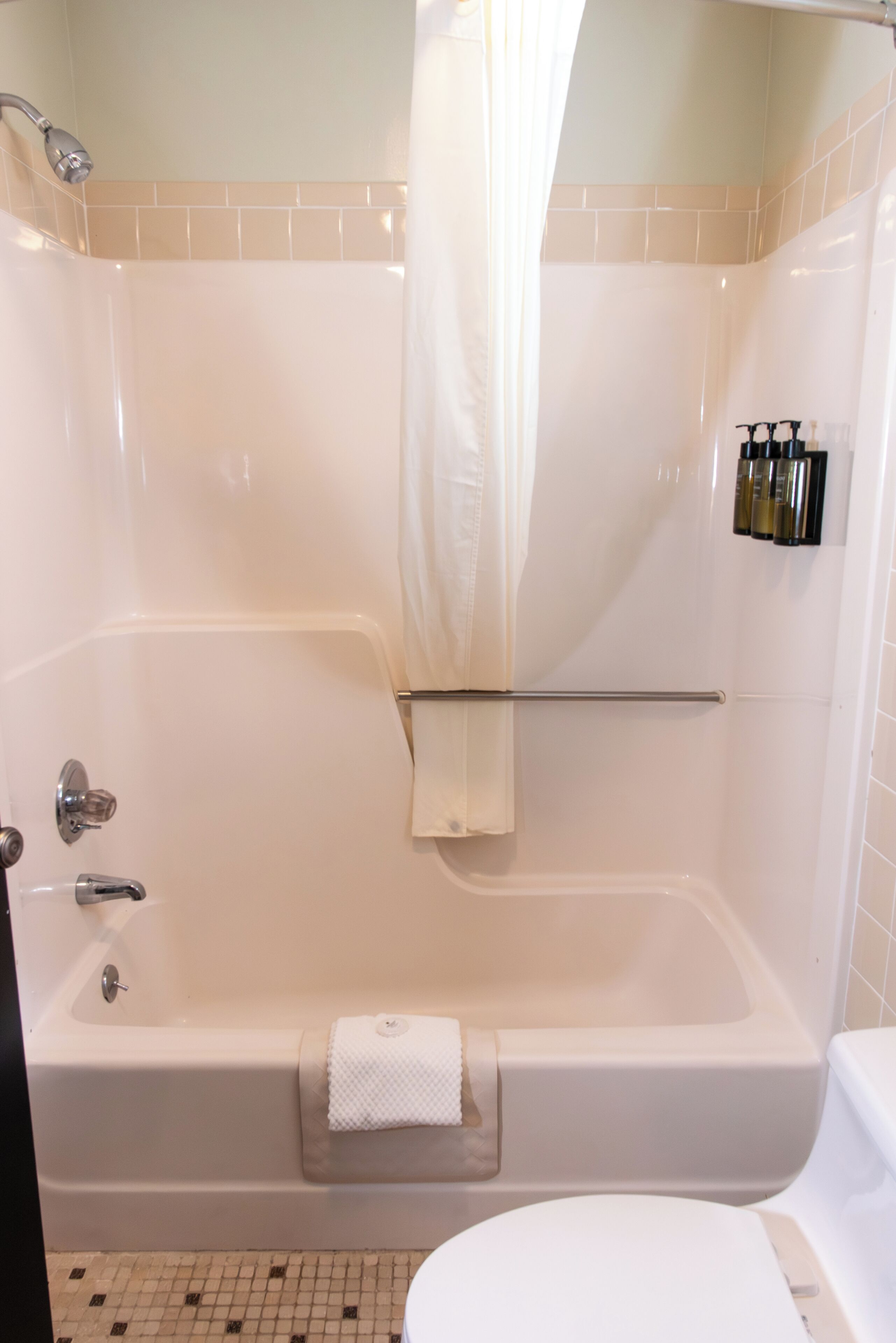A bathroom with a bathtub, a shower curtain, a towel rack, and a toilet.