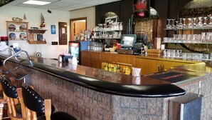 A bar area with a counter, chairs, and shelves of glassware. - Alexander House Motel (Park River)