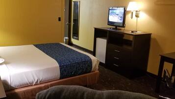 A hotel room with a bed, a desk, a television, and a lamp.