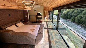 Un dormitorio con una cama grande, techo de madera y vista al río.