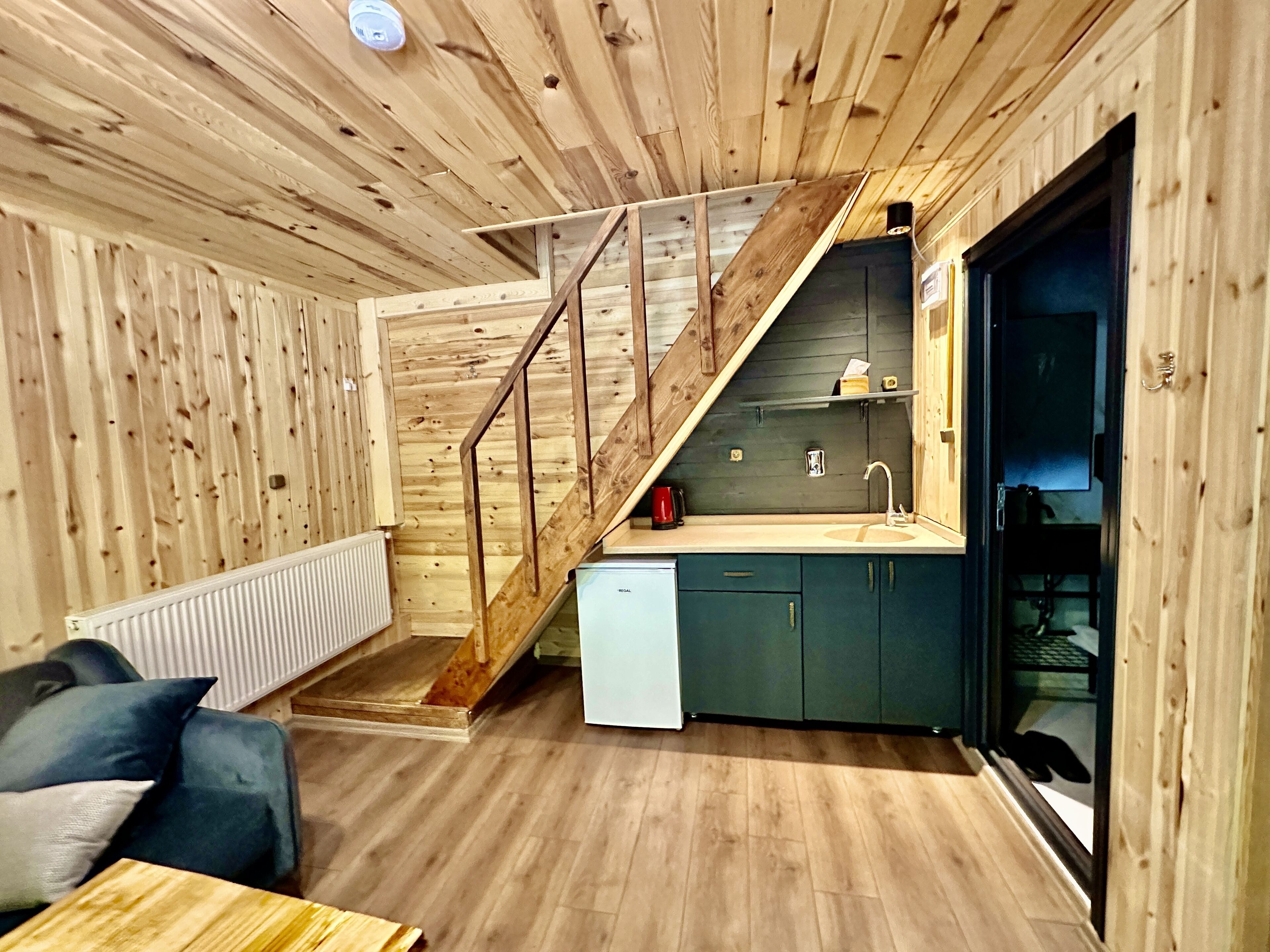 Cocina compacta y moderna con detalles de madera, lavavajillas integrado y un pequeño lavamanos.