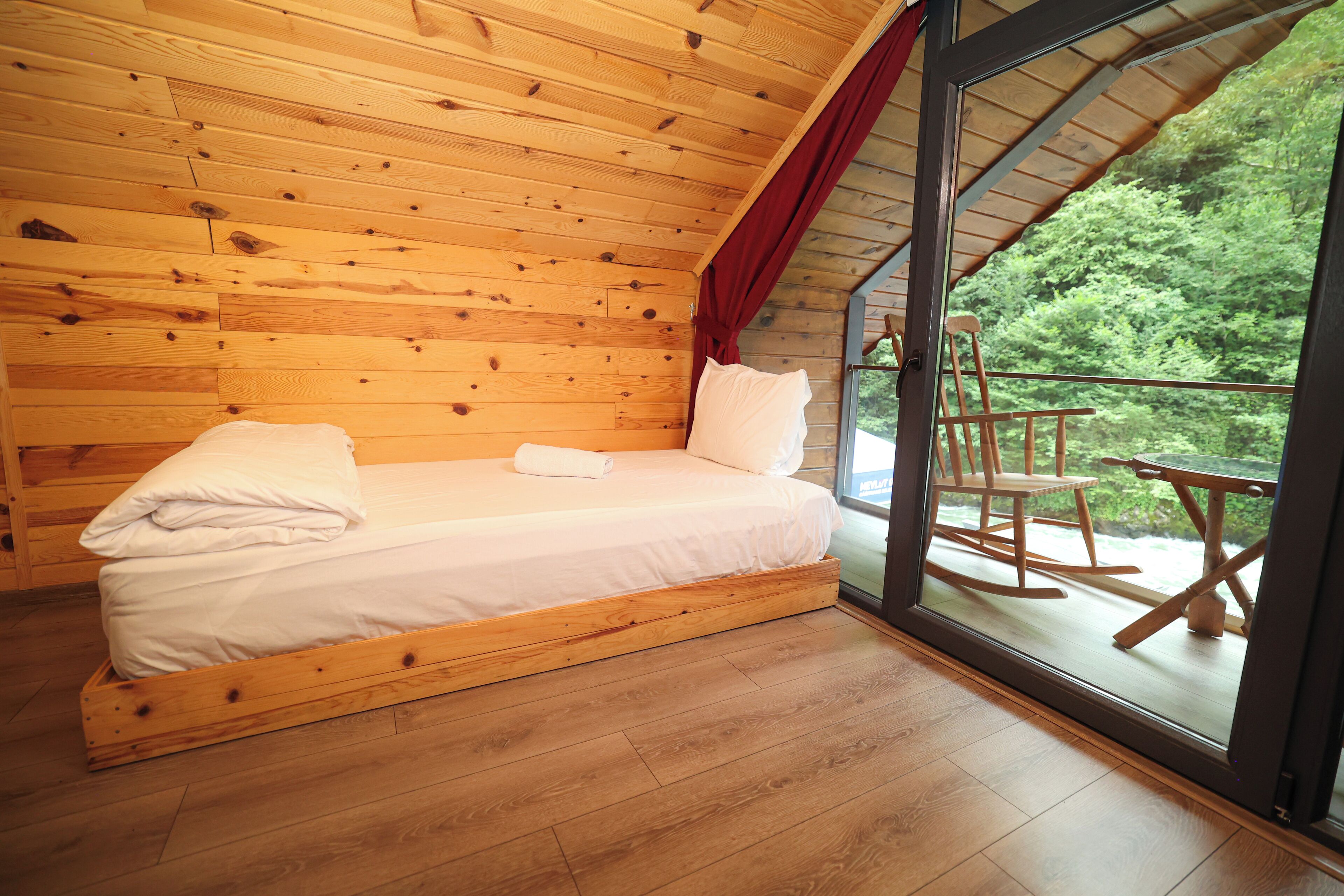 Une chambre dans une cabane en bois, avec un lit, une fenêtre et une vue sur l’extérieur.