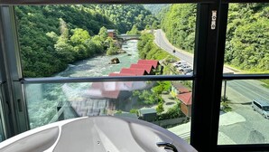 Una habitación con un ventanal grande que da a un río, un puente y una carretera con vehículos.